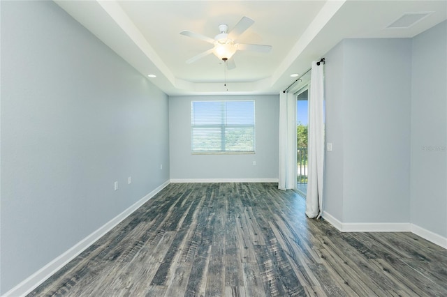 spare room featuring visible vents, a ceiling fan, wood finished floors, baseboards, and a raised ceiling