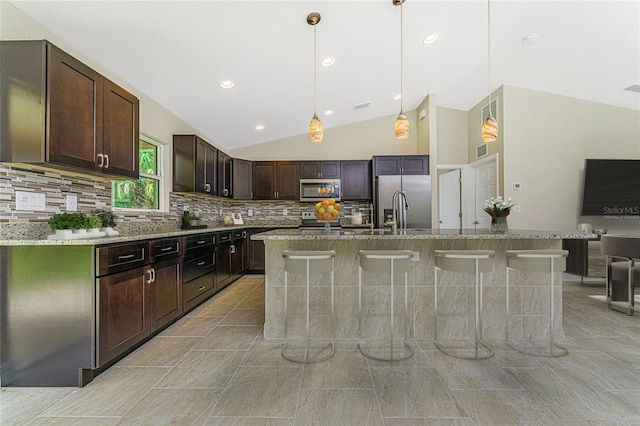 kitchen with a sink, a kitchen breakfast bar, dark brown cabinets, and stainless steel appliances