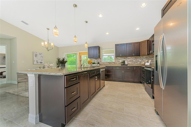 kitchen featuring a center island with sink, vaulted ceiling, decorative backsplash, appliances with stainless steel finishes, and hanging light fixtures