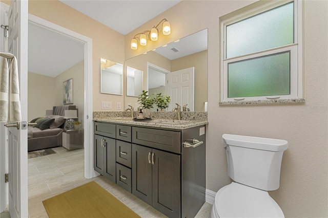 bathroom with double vanity, visible vents, toilet, and a sink