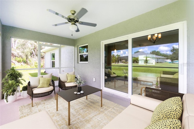 sunroom featuring ceiling fan with notable chandelier