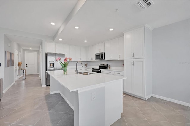 kitchen with an island with sink, a sink, light countertops, appliances with stainless steel finishes, and white cabinetry