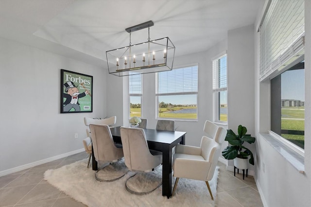 tiled dining area with baseboards, a healthy amount of sunlight, and a chandelier