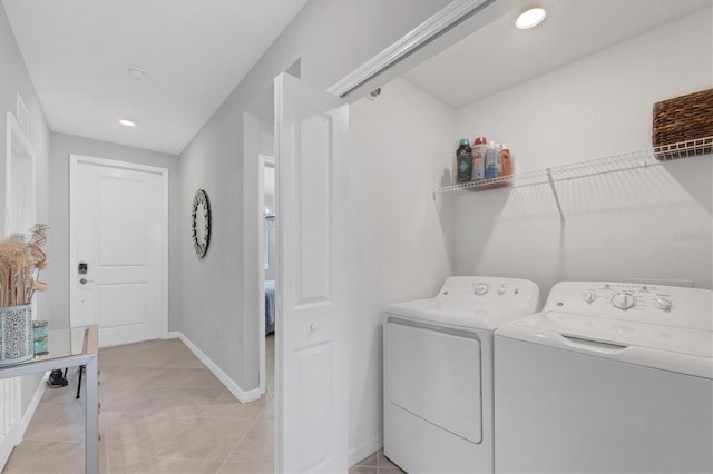 clothes washing area featuring washer and dryer, baseboards, laundry area, and light tile patterned floors