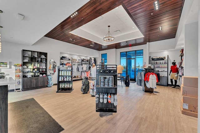 exercise room featuring a notable chandelier, wooden ceiling, a tray ceiling, and wood finished floors