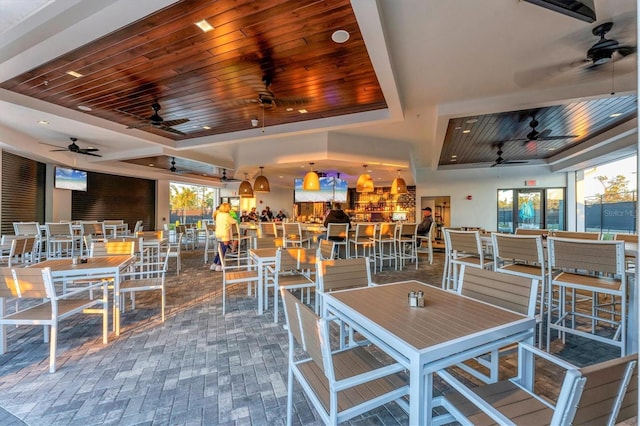 dining space featuring wooden ceiling, brick floor, and a tray ceiling