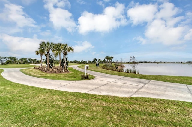 surrounding community with a water view and a lawn