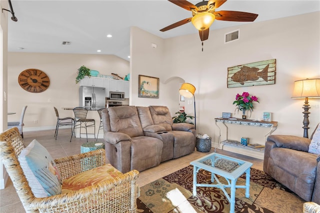 living area featuring light tile patterned floors, visible vents, arched walkways, and a ceiling fan