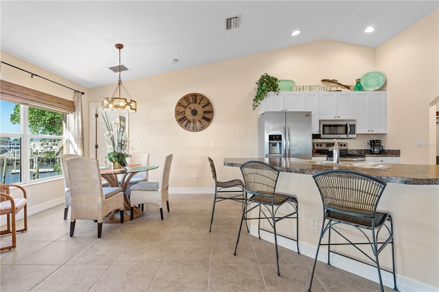 kitchen featuring visible vents, stainless steel appliances, pendant lighting, white cabinetry, and a kitchen breakfast bar