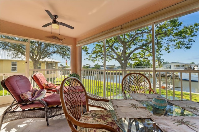 sunroom / solarium featuring a water view and a ceiling fan