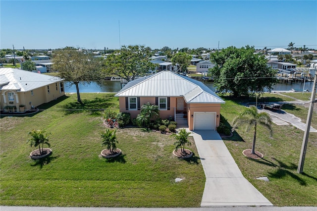 view of front of home with a front lawn, a water view, a residential view, stucco siding, and driveway