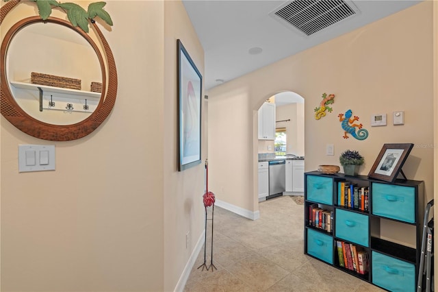 hallway featuring arched walkways, visible vents, baseboards, and light tile patterned floors