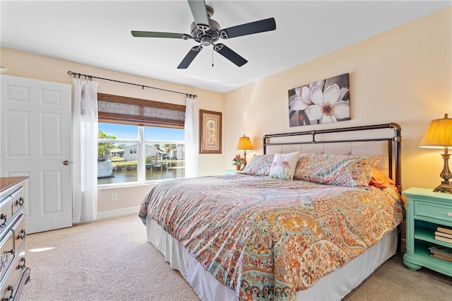 carpeted bedroom with baseboards, ceiling fan, and a water view