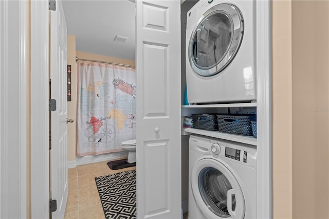 laundry area featuring tile patterned floors, stacked washer / dryer, and laundry area