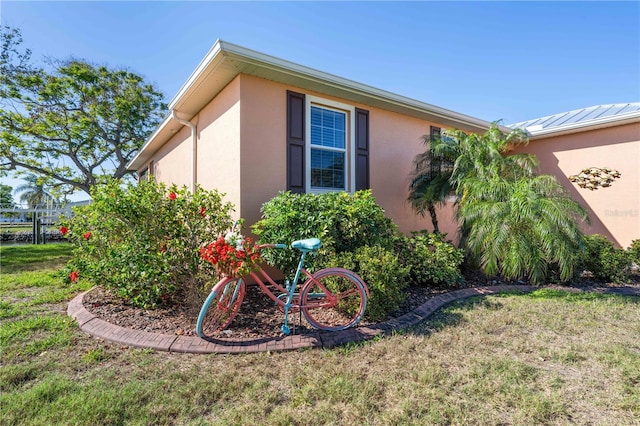 view of side of home with stucco siding and a lawn