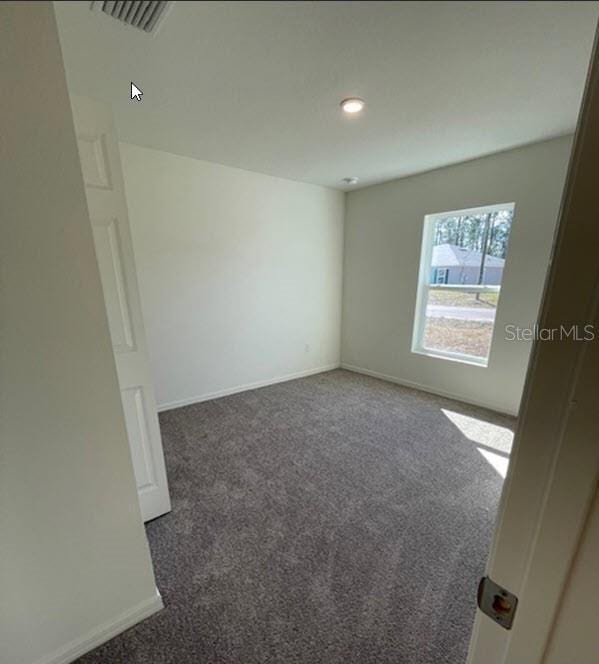 spare room with visible vents, baseboards, and carpet