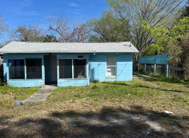 view of front facade featuring concrete block siding, a sunroom, and roof with shingles