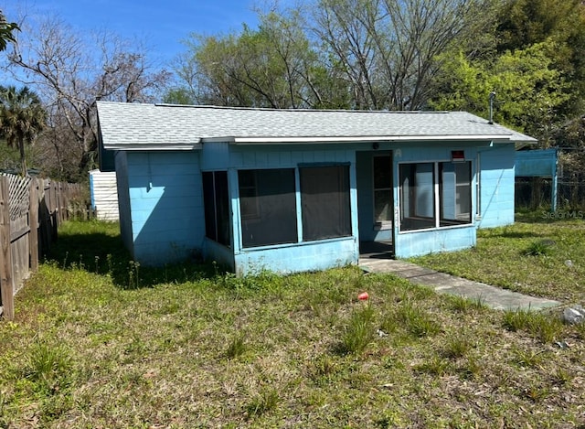 back of property featuring a yard, concrete block siding, a fenced backyard, and a sunroom