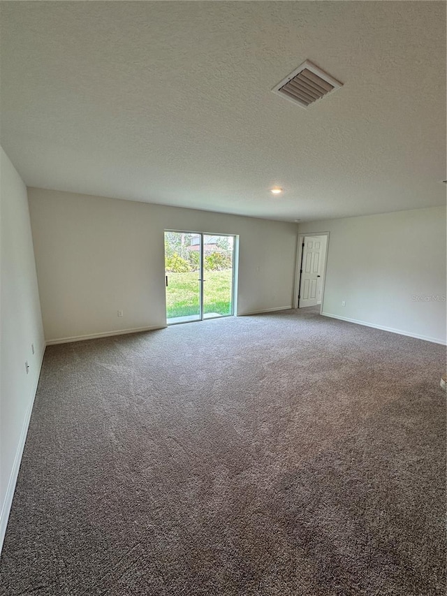 carpeted empty room with visible vents, a textured ceiling, and baseboards