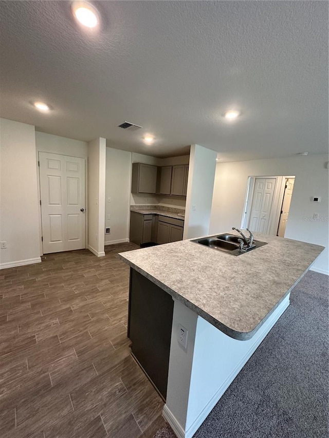 kitchen with a spacious island, baseboards, gray cabinets, dark wood-style floors, and a sink