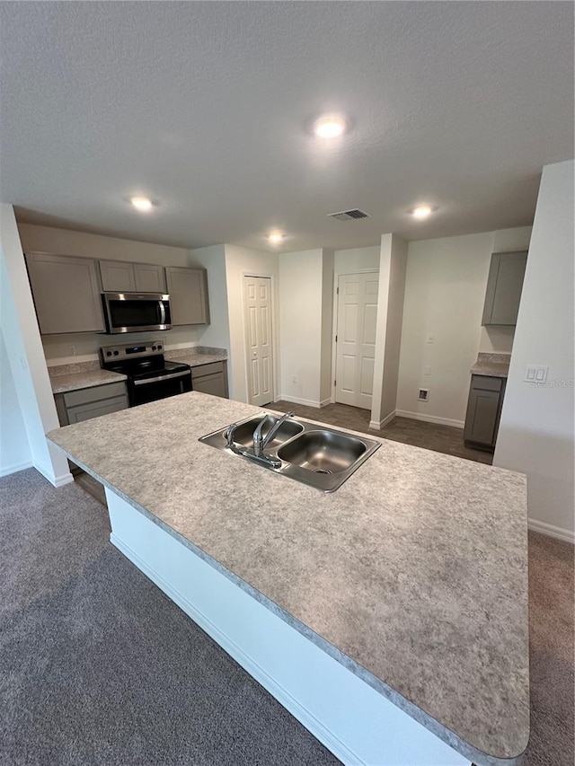 kitchen featuring visible vents, gray cabinets, a sink, dark carpet, and stainless steel appliances