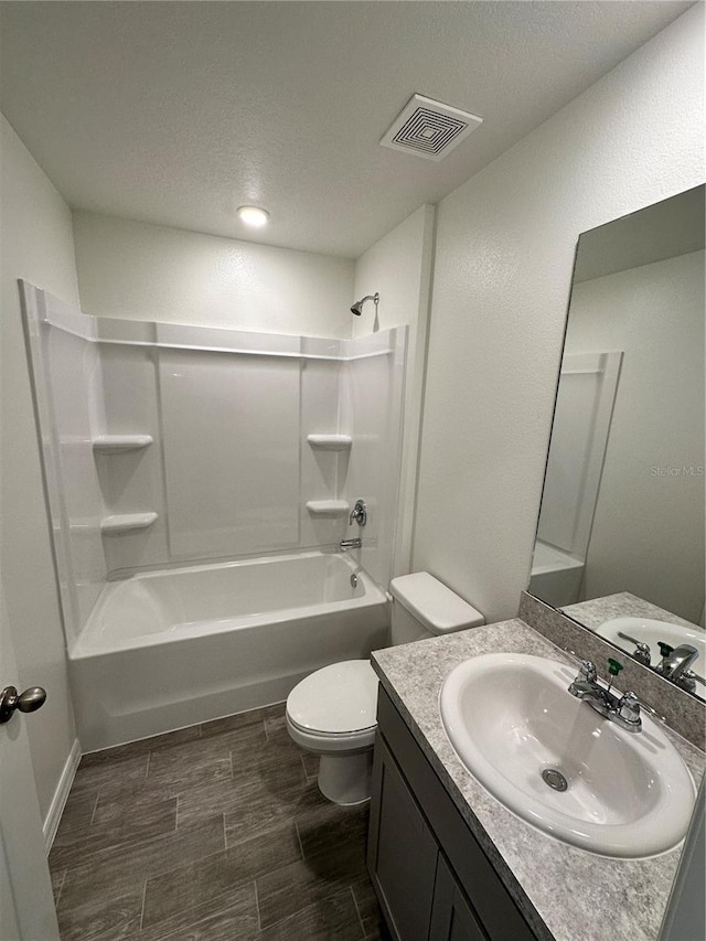 full bathroom with visible vents, toilet, wood tiled floor,  shower combination, and vanity