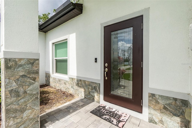 entrance to property featuring stone siding and stucco siding