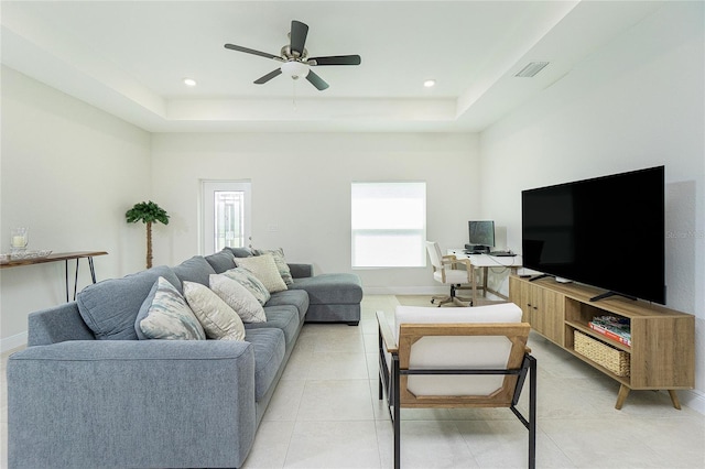 living room featuring visible vents, a raised ceiling, baseboards, and light tile patterned flooring