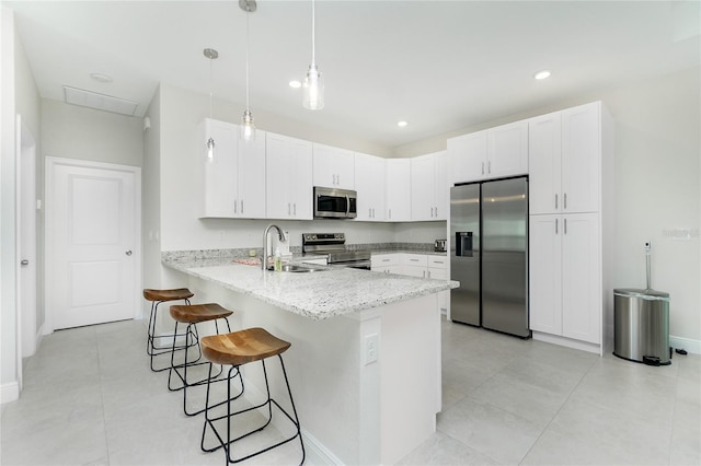 kitchen featuring a breakfast bar, light stone counters, a peninsula, stainless steel appliances, and a sink