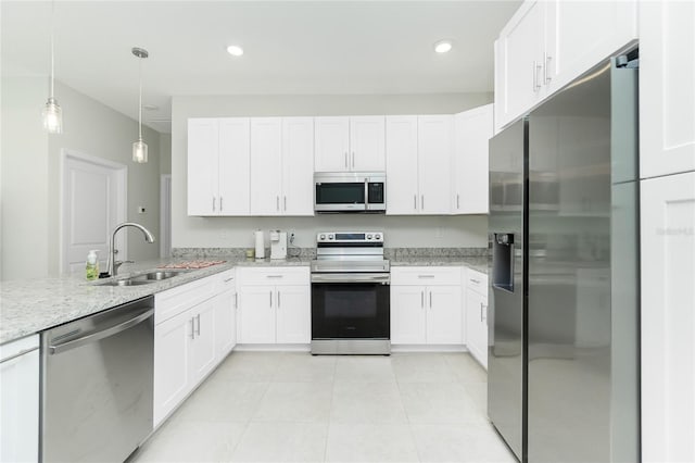 kitchen featuring a sink, light stone counters, appliances with stainless steel finishes, and white cabinets