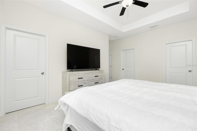 bedroom featuring light tile patterned floors, visible vents, a raised ceiling, and a ceiling fan