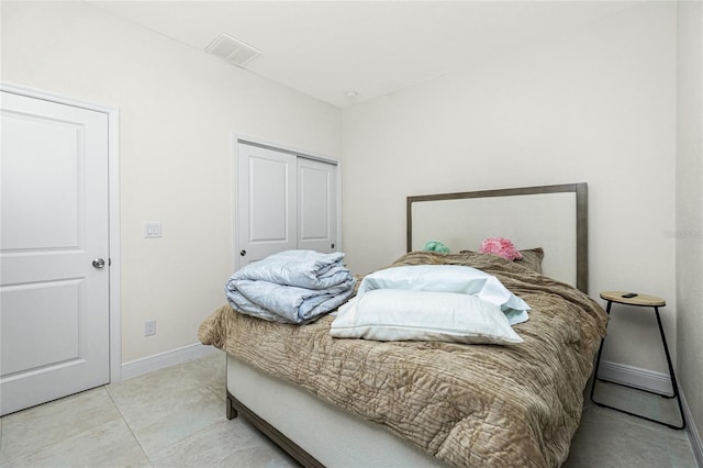 bedroom featuring light tile patterned flooring, visible vents, baseboards, and a closet