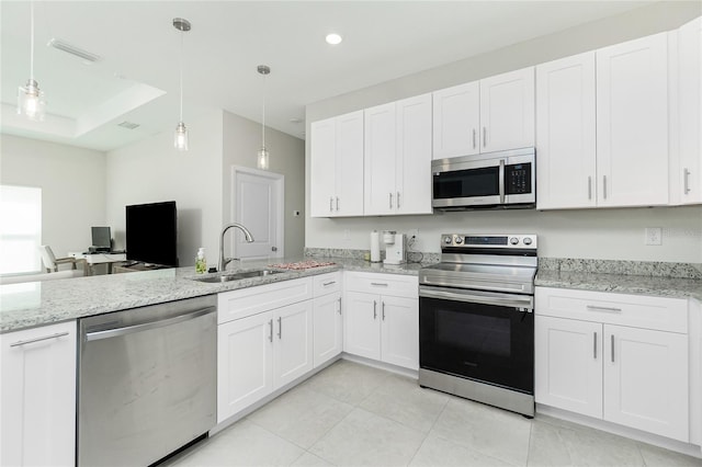 kitchen featuring a sink, decorative light fixtures, appliances with stainless steel finishes, and white cabinets