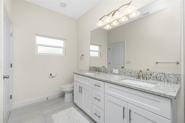 bathroom featuring double vanity, toilet, visible vents, and a sink