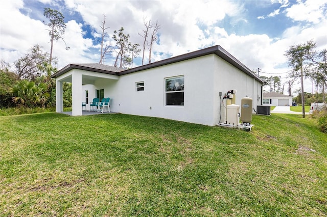 rear view of property featuring a patio, a lawn, central AC, and stucco siding