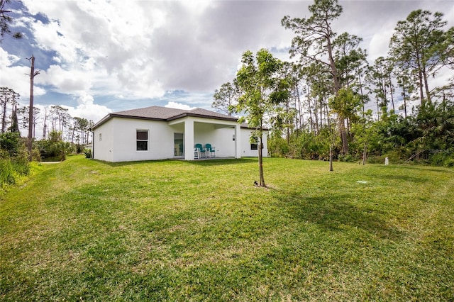 rear view of house with a yard and stucco siding