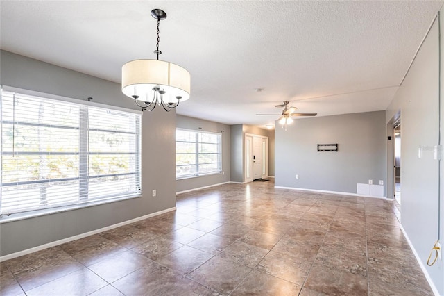 spare room featuring baseboards, a textured ceiling, and ceiling fan with notable chandelier