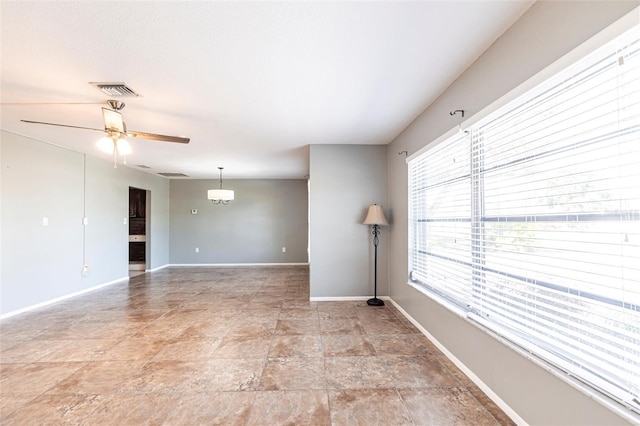 unfurnished room with visible vents, a ceiling fan, and baseboards