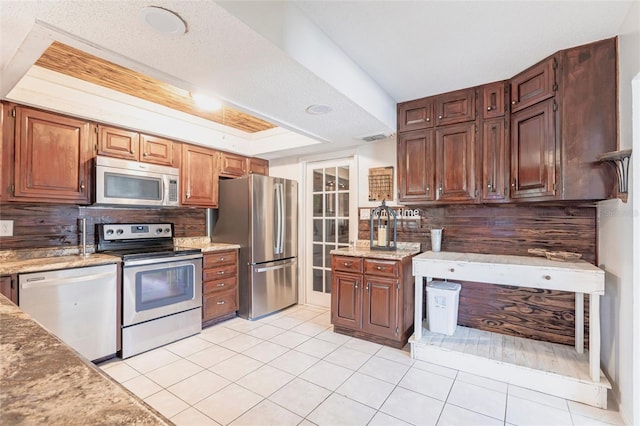 kitchen with tasteful backsplash, visible vents, light tile patterned floors, stainless steel appliances, and a raised ceiling