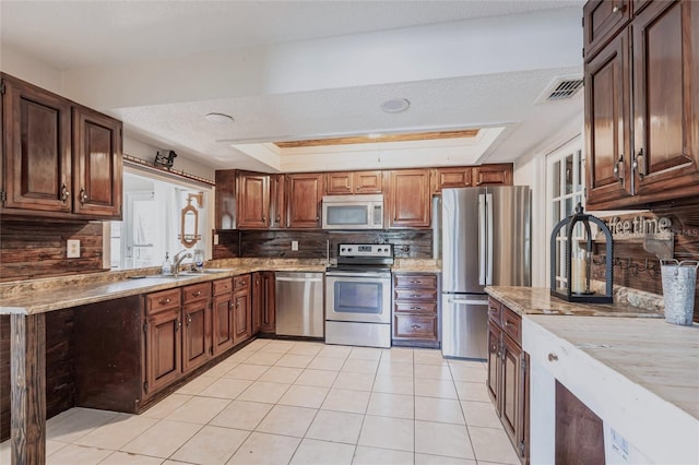 kitchen with visible vents, stainless steel appliances, a raised ceiling, and a sink