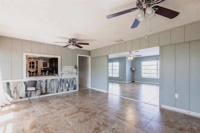 unfurnished living room with visible vents, baseboards, and a textured ceiling