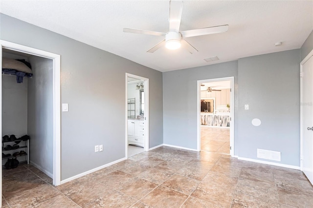 unfurnished bedroom featuring ensuite bath, a spacious closet, baseboards, and visible vents