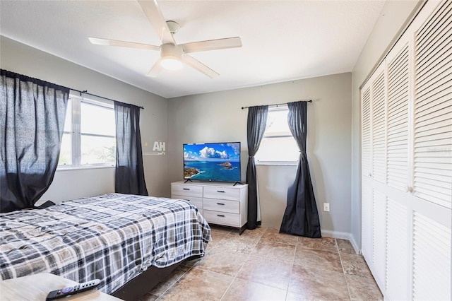 bedroom featuring multiple windows, a ceiling fan, a closet, and baseboards