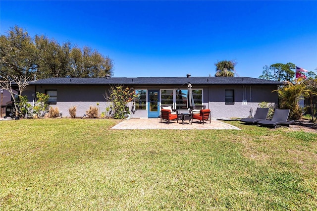 back of property with a patio area, a lawn, and stucco siding