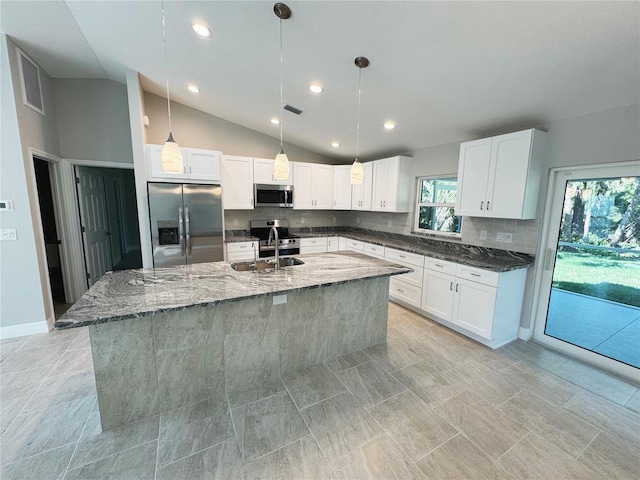 kitchen featuring dark stone countertops, white cabinets, appliances with stainless steel finishes, and a sink