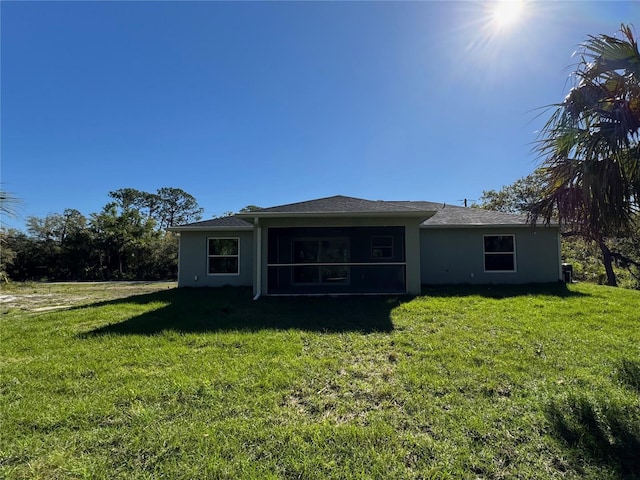 back of property with a yard, a sunroom, and stucco siding