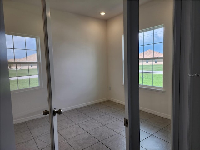 unfurnished room with light tile patterned floors and baseboards