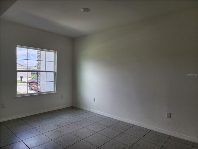 spare room with tile patterned flooring and baseboards