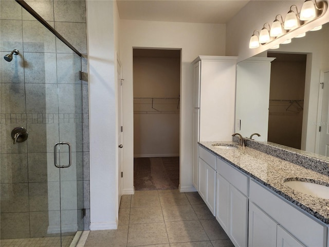 bathroom with a sink, double vanity, a shower stall, and tile patterned floors