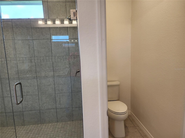 bathroom featuring tile patterned floors, baseboards, toilet, and a stall shower